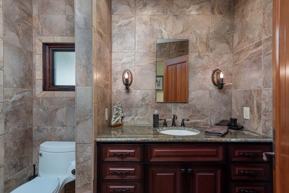 barber using styling spray on young man with black hair, short on sides and long in a quiff on top